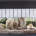 Modern Courtyard Garden With Stacked Rocks Water Feature And Lush Green Plants Behind Glass Windows