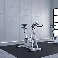 Two Stationary Exercise Bikes On Black Mat With Brick Wall And Gray Floor