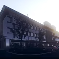 Modern Hotel Building With White And Brown Facade Large Glass Windows Trees And Parking Area