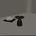 Black Side Table with Round Tray and Conical Base Near White Plush on Black Mat