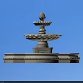 White Multi Tiered Water Fountain With Decorative Base Against Blue Sky