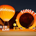 Illuminated Art Installation With Orange Hot Air Balloon Welcome Sign And Sunset Ring At Nighttime