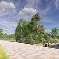 Scenic Waterfront Landscape With Paved Walkway Green Grass Trees Blue Sky And Calm Water