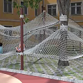 Kindergarten Outdoor Playground Featuring Climbing Net Structure With Children Playing In Green Grass