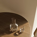 Clear Glass Cup And Carafe On Wooden Round Table With Light Colored Wall And Sunlight