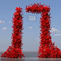 Red Flower Covered Art Installation With Tall Columnar Structures Against Blue Sky