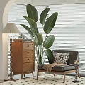 Comfortable Lounge Chair with Patterned Pillow Throw Blanket Wooden Chest Lamp and Large Green Plant