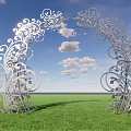 Silver Arched Gate With Intricate Scroll Designs Against Green Grass And Blue Sky