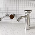 Stainless Steel Kitchen Faucet Against White Grid Tile Wall And Speckled Countertop