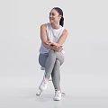 Woman Sitting On Chair Crossed Arms Wearing White Sleeveless Top Gray Leggings White Sneakers Smiling