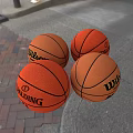 Four Wilson and Spalding Basketball Sports Equipment on Brick and Gray Ground Surface
