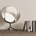 Silver Spherical Table Lamp With Tripod Base And Stacked Books On Desk