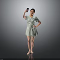 Woman Posing in Light Green Dress Taking Selfie with Mobile Phone Against Gray Background