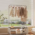 Metal Clothes Rack Holding Light Colored Clothes With Storage Basket And Plant By Window