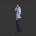 A Man Talking on the Phone in Blue Shirt and Dark Pants Against Gray Background