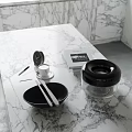 Elegant Decorative Ornament Set with Black Bowl Silver Utensils Transparent Lidded Container on Marble Countertop