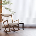 Wooden Rocking Chair With White Cushion And Side Table Vase Green Plant Against White Blinds