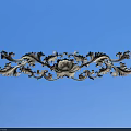 Ornate Metallic Carving With Intricate Curved Patterns And Floral Elements On Blue Background