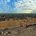 Ancient Architecture Construction Site With Workers And Materials Amid Cityscape And Cloudy Sky