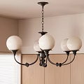 Black Frame Chandelier With White Spherical Shades In Room With Wooden Cabinets And Blinds