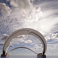 Modern Streamlined Sculpture With Curved Metallic Design Against Blue Sky And Water Reflection
