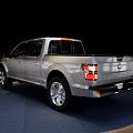 Shiny Silver Four Door Pickup Truck On Circular Display Platform With Black Background
