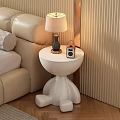 White Round Side Table with Distinctive Legs Next to Beige Sofa Holding Lamp and Radio
