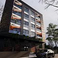 Modern Multi Storey Building With Glass Windows Balconies And Green Trees Around