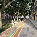 Garden Landscape With Tree Lined Walkway Colorful Paved Path And Benches Near Commercial Buildings