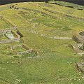Archaeological Terrain With Green Grass Stone Walls And Ancient Ruined Structures