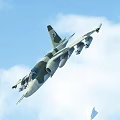 Camouflage Fighter Jet With Red Tail Emblem Launching Missile In Blue Sky