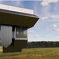 Modern Suspended Metallic Architectural Structure With Angular Roofs Over Grassland And Sky