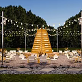 Scenic Campsite With Pyramid Shaped Wooden Structure White Chairs Tables And String Lights