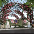 Iron Arbor Decorated With Pink Red Flowers Balloons Palm Trees And Greenery In Outdoor Setting