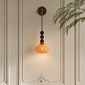 Elegant Wall Lamp With Orange Lampshade Black Bead Decoration On Light Wall With Green Leaves