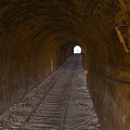 Old Stone Tunnel Interior With Wooden Railway Track And Distant Light
