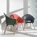 Stylish Leisure Chairs Green Pink And Dark Blue With Wooden Legs Against White Wall Background