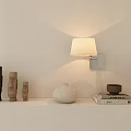Minimalist Wall Sconce with White Shade Wooden Figurines White Vase and Books on Shelf