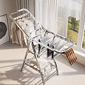 Silver Foldable Metal Clothes Drying Rack With Hanging Clothes Near Window In Laundry Room