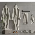 Soft Towels And Cozy Robes Arranged With Slippers On Gray Tiled Wall