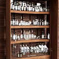 Wine Bottles and Glasses Neatly Displayed on Multiple Shelves in Wooden Cabinet