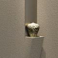 Ceramic Vessel With Intricate Patterns Showcased In Wall Niche Against Gray Textured Wall