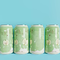 Four Milk Flavor Beverage Cans With Green Apple Design On Light Blue Background