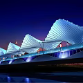 White Wing Structure Scenic Bridge At Night With City Skyline And Water Reflection
