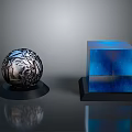 Silver Sphere with Intricate Patterns and Blue Cubes on Black Base with Reflections