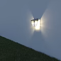 Lit Wall Light Mounted on Exterior Wall with Green Grass Below and Light Sky