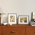 Two Vintage Picture Frames With Portraits On Wooden Dresser With Lamp Mugs And Books