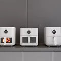 Three White Modern Kitchen Air Fryers On Gray Countertop With Cabinets