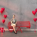 Red Public Bench With Heart Shaped Balloons And Gift Boxes Against Gray Wall