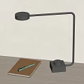 Modern Black Desk Lamp with Curved Arm on Wooden Tabletop with Notebook and Green Pen